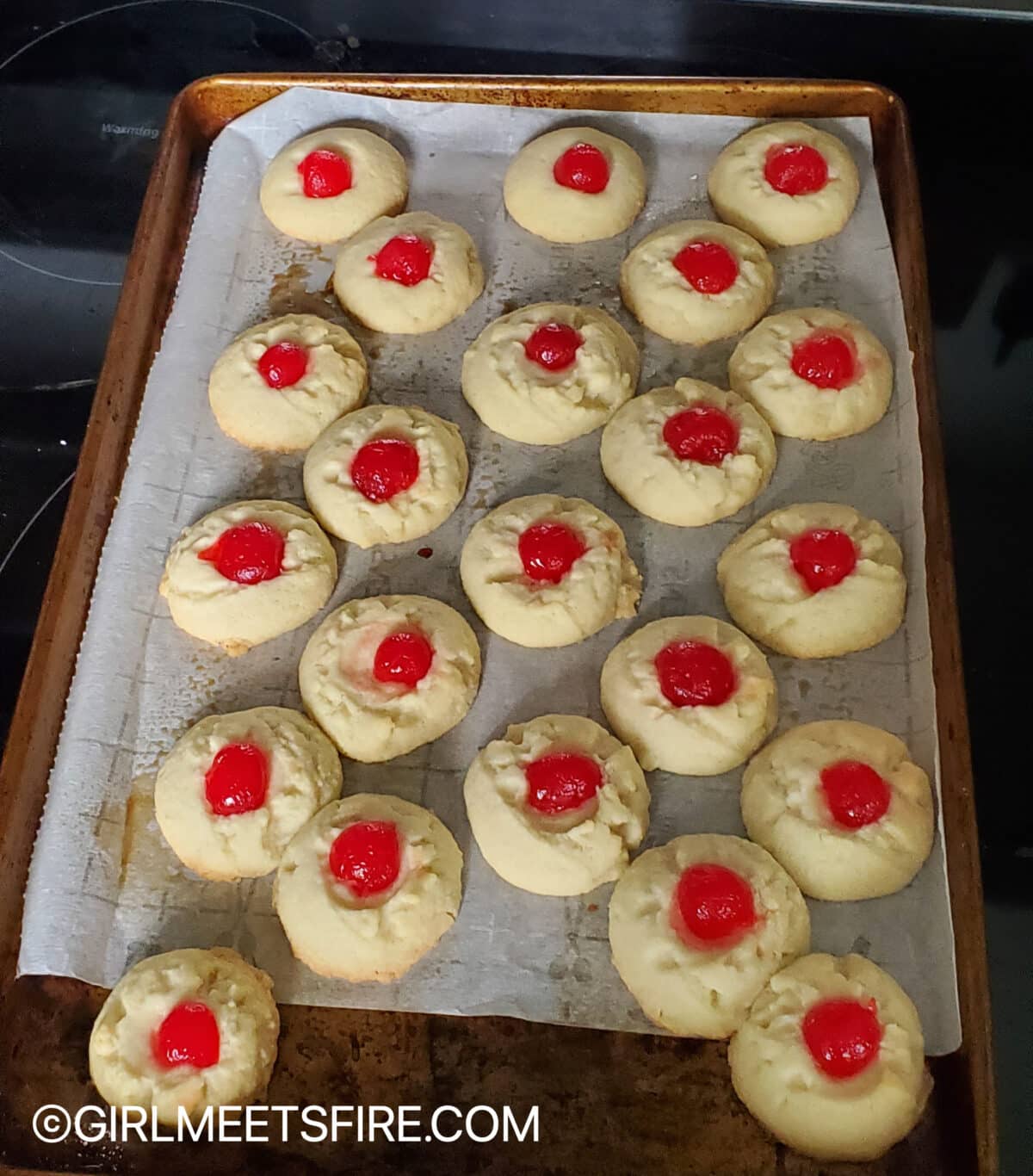 Cookie pan with polvorones straight out of the oven, topped with halved maraschino cherries
