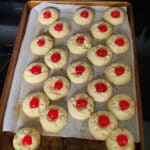 a cookie tray with polvorones topped with maraschino cherries